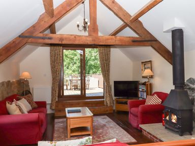 A living room with a sofa, coffee table, and television at The Cottage in Sampford Courtenay