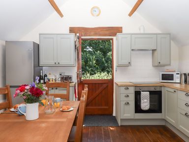 A kitchen with a wooden table and chairs at The Cottage in Sampford Courtenay