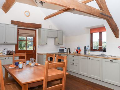 A kitchen with wooden furniture and appliances at The Cottage in Sampford Courtenay
