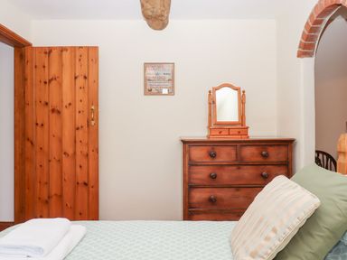 A bedroom with a mirror and chest of drawers at The Cottage in Sampford Courtenay