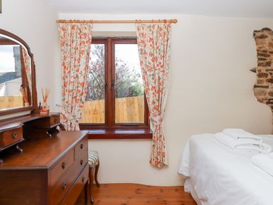 A bedroom with a dresser and a window at The Cottage in Sampford Courtenay