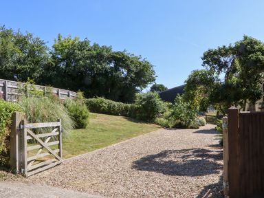A garden with a gravel path and a gate at The Cottage in Sampford Courtenay