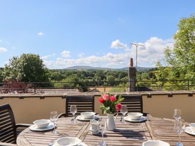 An outdoor dining area with a table set and flowers at The Cottage in Sampford Courtenay