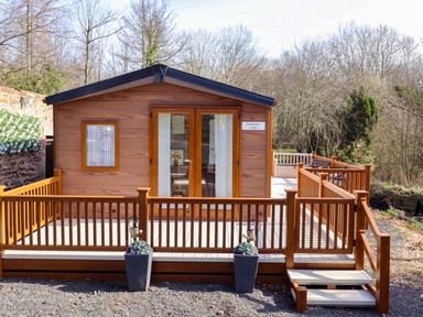 A lodge with a deck and railings at Gardeners Lodge in 