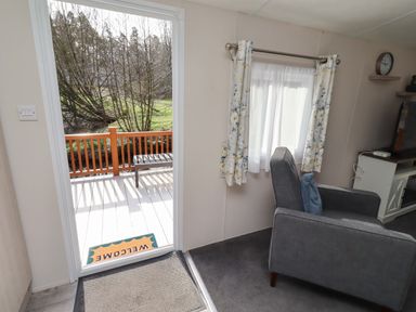 A living room with a door leading to a deck at Gardeners Lodge