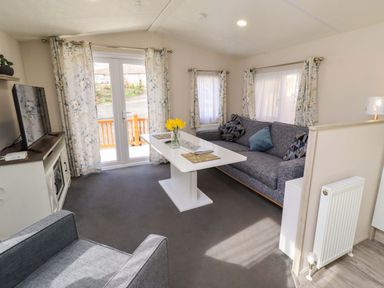 A living room with a sofa and television at Gardeners Lodge