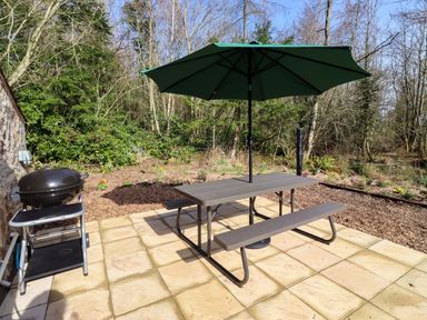 A picnic table with an umbrella and grill at Gardeners Lodge
