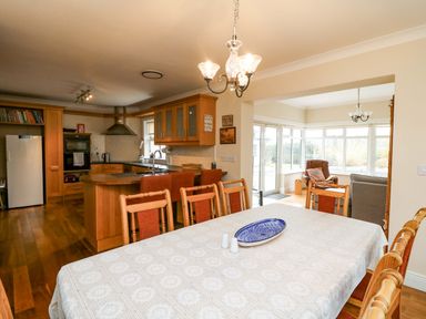 A kitchen with a dining table and a view into a conservatory at Sunnyside River Chapel