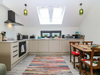 A kitchen with appliances and a dining table at Trwyn Cam in Brynrefail near Llanberis