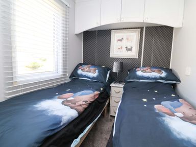 A bedroom with twin beds and a window at Grosvenor 10 in Llanarmon-Yn-Ial