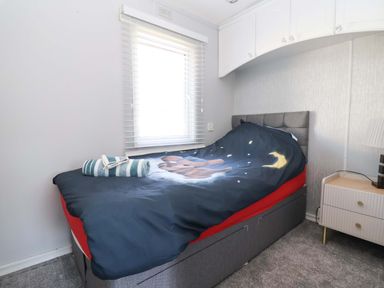 A bedroom with a bed and window at Grosvenor 10 in Llanarmon-Yn-Ial