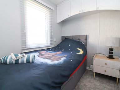 A bedroom with a bed and patterned blanket at Grosvenor 10 in Llanarmon-Yn-Ial