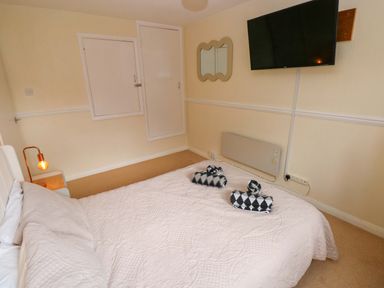 A bedroom with a bed, television, and mirror at The Wool Pack in Tenby