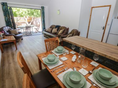 A dining room with a table set for dinner and a sofa at Brookview Kingfisher in Haverfordwest
