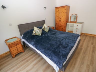 A bedroom with a bed and wooden furniture at Brookview Kingfisher in Haverfordwest
