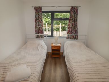 A bedroom with two beds and a nightstand at Brookview Goldfinch in Haverfordwest