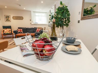A dining table with a fruit basket and dishes at Tipsy Turtle in Weymouth