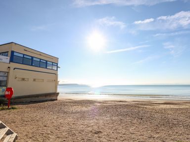 A beach with a building and water at Rose Cottage in Osmington