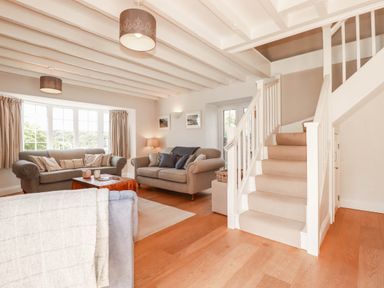 A living room with seating and stairs at Bryher Cottage St Mawgan