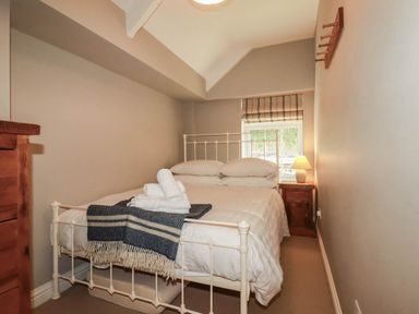 A bedroom with a bed and a lamp at Bryher Cottage St Mawgan