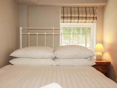 A bedroom with a bed and window at Bryher Cottage in St Mawgan