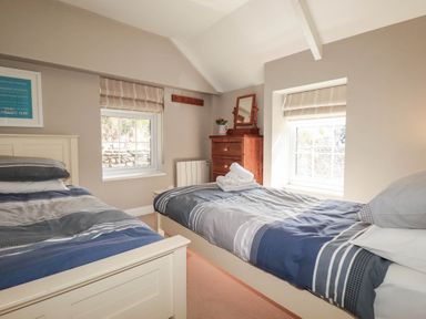 A bedroom with two beds and a dresser at Bryher Cottage St Mawgan