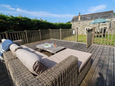 A deck with a sofa and coffee table at Bryher Cottage St Mawgan