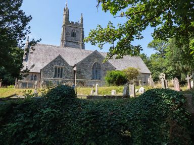 A church with gravestones and trees at Bryher Cottage St Mawgan