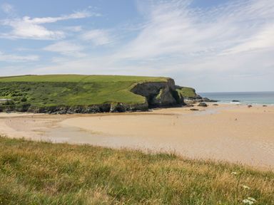 A beach with sand and cliffs at Bryher Cottage in St Mawgan