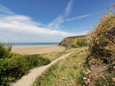 A beach with a path leading to the ocean at Bryher Cottage in St Mawgan