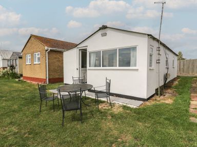 A house with a table and chairs on grass at Watersmeet - 85 @ Park Avenue Holiday Village, Leysdown-On-Sea, Kent