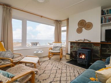 A living room with a sea view and a fireplace at Wootton Gray in Penzance