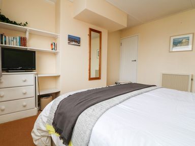 A bedroom with a bed and shelves at Wootton Gray in Penzance
