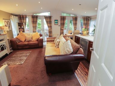 A living room with a sofa and dining area at Jodene Lodge, Redwood 2 Bowness-On-Windermere