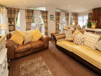 A living room with a sofa and a dining table at Jodene Lodge, Redwood 2 Bowness-On-Windermere