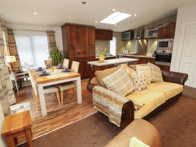 A kitchen and dining area with a table and sofa at Jodene Lodge, Redwood 2 Bowness-On-Windermere