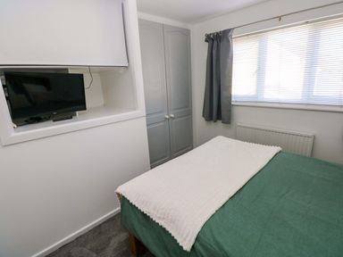 A bedroom with a bed, television, and wardrobe at The Gower Gateway in Gowerton near Swansea