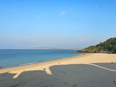 A beach with ocean and hills at Dog-friendly lodge, steps to St Ives train in Hayle