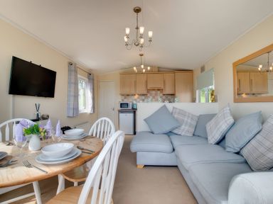 A living room with dining area and kitchen appliances at Pet-friendly lodge with hot tub near the coast