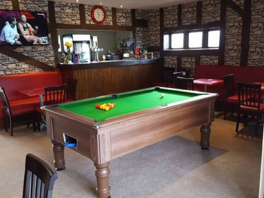 A snug area with a pool table and a bar counter at Pet-friendly lodge with hot tub near the coast