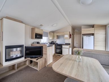 A kitchen area with a dining table and appliances at Pet-friendly lodge near Fistral Beach, Newquay