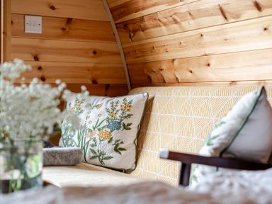 A couch with a decorative pillow and flower arrangement at Peaceful pod with bay views, walk to 3 beaches St Ives