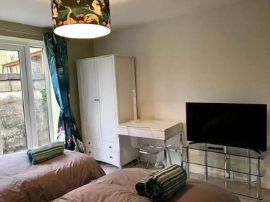 A bedroom with two beds, a desk and a television at tbc