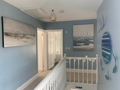 A hallway with paintings and a light fixture at tbc 