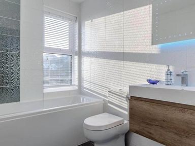 A bathroom with a bathtub, toilet, and sink at tbc