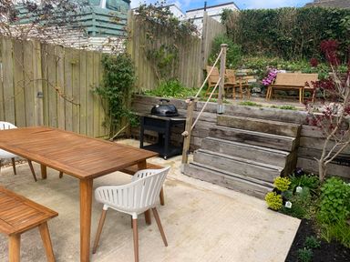 A garden with a dining table and chairs and a barbecue grill at tbc