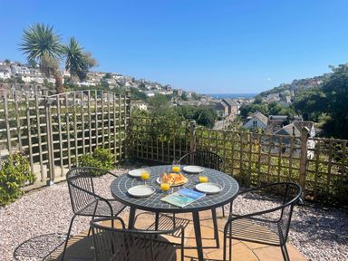 An outdoor dining area with a table and chairs overlooking the landscape at tbc