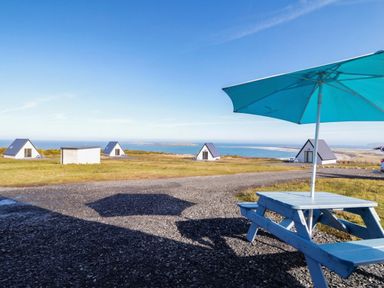 A picnic table with an umbrella and cabins near the beach at Cabin 9 Inish Beag, Gortahawk