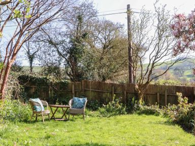 A garden with chairs and a table at Upper Frogpool Cottage in Crediton