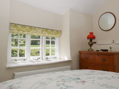 A bedroom with a window and a dresser at Upper Frogpool Cottage in Crediton
